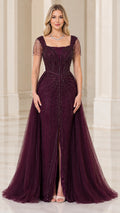 Front view of woman wearing burgundy square neck beaded evening gown with front slit and tulle overskirt