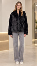 Front view of model wearing black beaded faux fur jacket with wide-leg denim