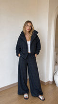 Model wearing black plaid high-collar jacket and matching wide-leg trousers front view