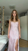 Front view of model wearing light pink satin maxi slip dress with lace trim and high slit