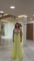 Front view of model wearing a light yellow halter embellished evening gown