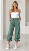 Front view of model wearing sage green relaxed cinch-bottom joggers with white tank top and sneakers
