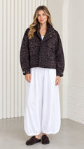 Front view of model wearing dark brown leopard print cropped jacket with wide white trousers