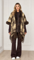 Woman wearing olive khaki plaid poncho with faux fur collar and fringe hem - front view