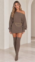 Model wearing taupe off the shoulder ribbed knit mini sweater dress with chain belt and thigh high boots front view