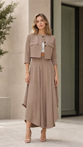 Model wearing taupe cropped jacket and asymmetrical maxi skirt two-piece set front view
